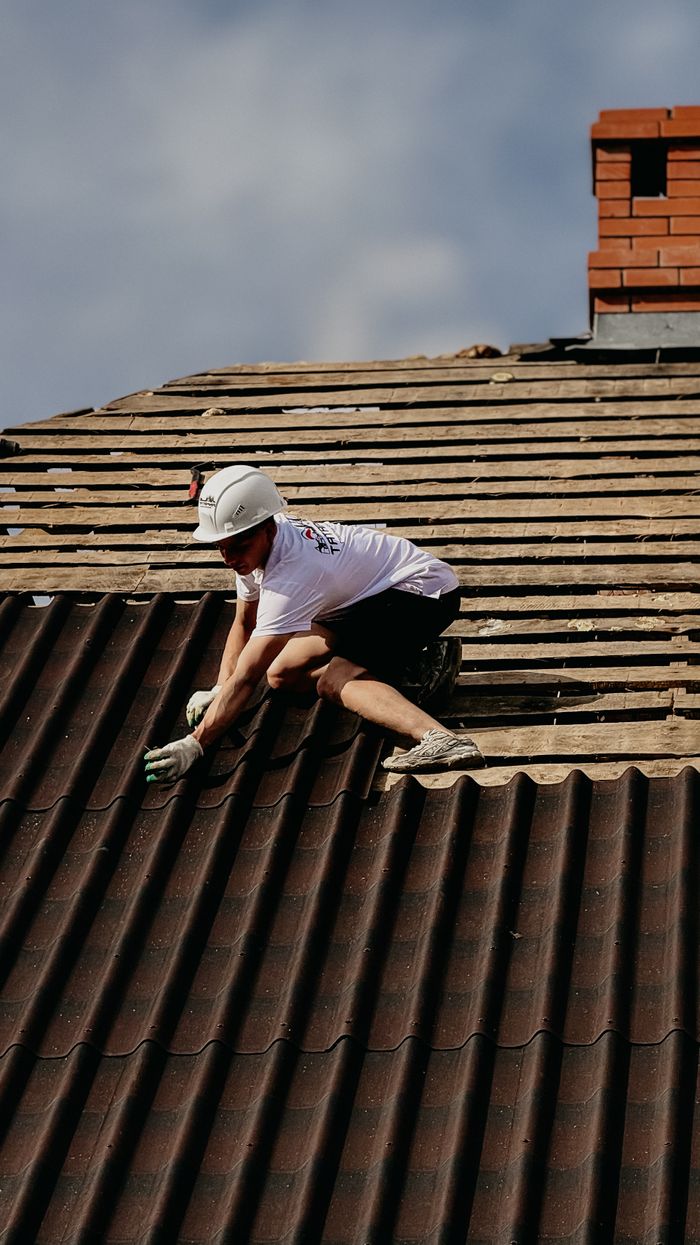 Crafting Captivating Headlines: Your awesome post title goes here A construction worker installs roofing tiles wearing protective gear on a sloped rooftop.
